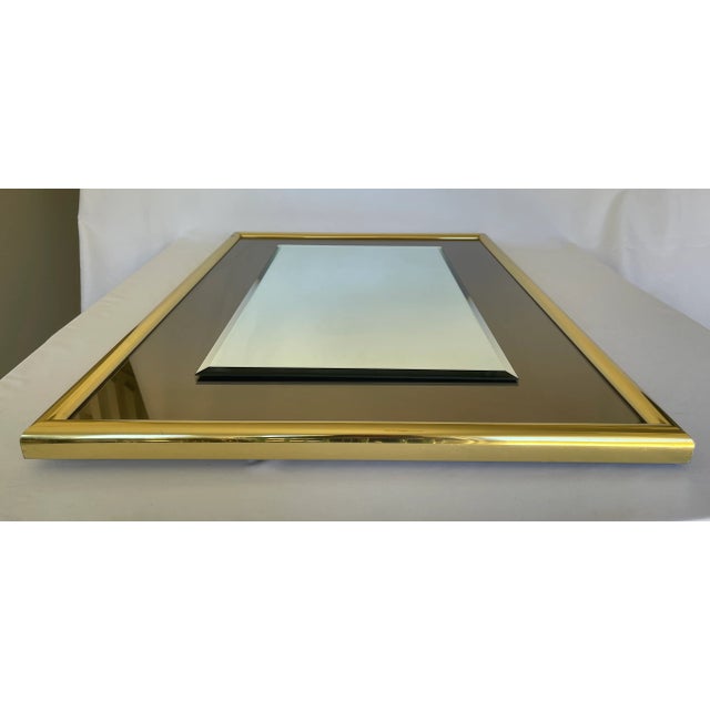 1970s rectangular mirror with smoke glass border and brass frame. May be hung vertically or horizontally.