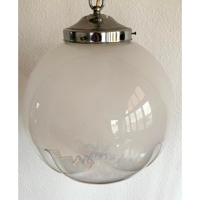 Beautiful vintage Murano glass hanging lamp designed AV Mazzega. It features a chrome metal fixture, chain, and ceiling...