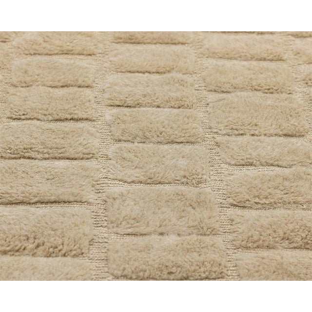 Minimalist hand-knotted wool rug with a textured checkerboard pattern in Velvet Fawn tones offers a plush feel and a...