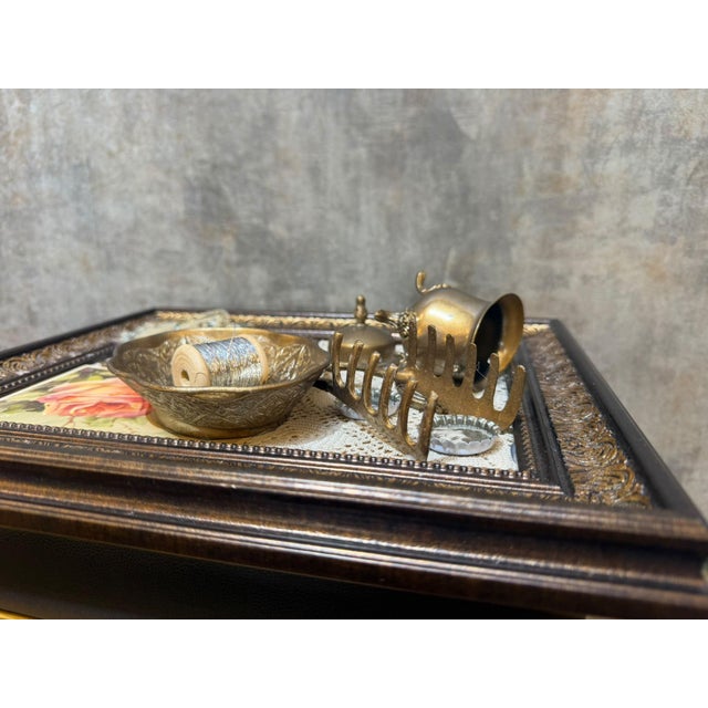 A framed assemblage of vintage objects, mounted on a crocheted lace ground inside a richly ornamented wood frame. The...
