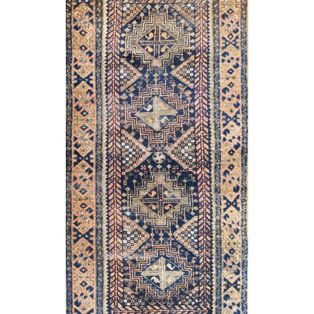 An early 20th-century Persian Baluch rug, handwoven in a rich, earthy palette of brown, orange, faded crimson, black, and...