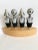 Set of 4 wine stoppers. Polished nickel color with black rubber ribbed bases. Sit in a light colored wood holder. Stoppers...