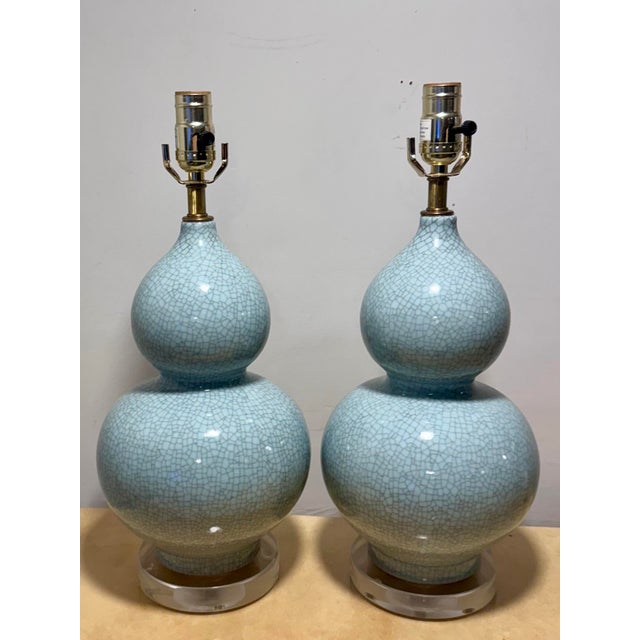 A very charming pair of modern double gourd Porcelain lamps in a crackle glaze with lucite bases and single brass hardware.