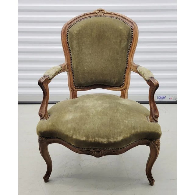A lovely antique Louis XV armchair with velvet green upholstery, natural wood frame decorated with hand carved flowers....