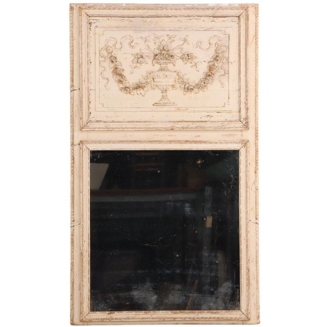 This antique mirror features a carved-wood plaque top, typical of trumeau design, with urn of flowers flanked by swags....