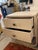 Pair of washed wood 2-drawer nightstands wrapped in linen and coated with a shellac. The drawers have rounded pulls in...