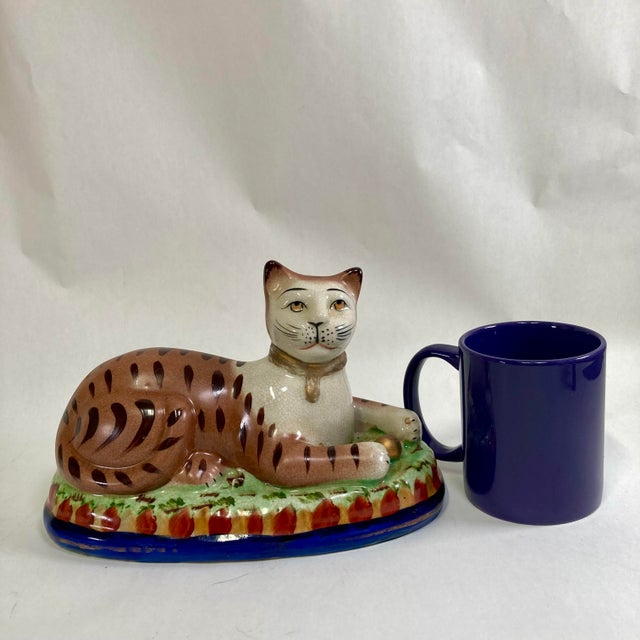 Wonderful recumbent mantle cat painted in folk art whimsical colors. I love the ball in his front pays. Nice large size...