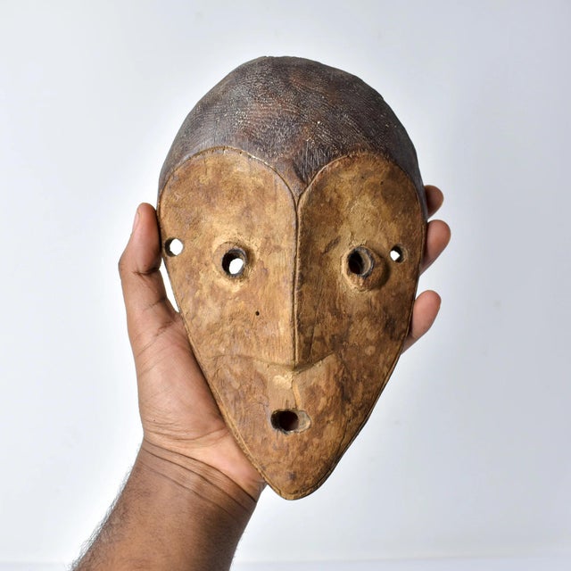 Lega masks, wooden and featuring elongated faces with a central ridge, almond-shaped eyes, and symbolic geometric...