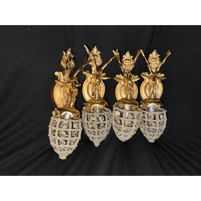 A rare and decorative set of four French Louis XVI-style wall lamps / sconces, crafted circa 1970 from gilt bronze with...