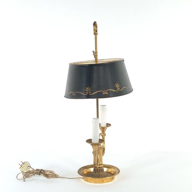 This elegant bouillotte lamp features a dark metal shade with gilt floral motifs suspended above a brass base with two...