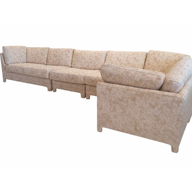 Neutral upholstered modular sectional sofa in the style of Milo Baughman featuring a soft tone-on-tone woven pattern and a...