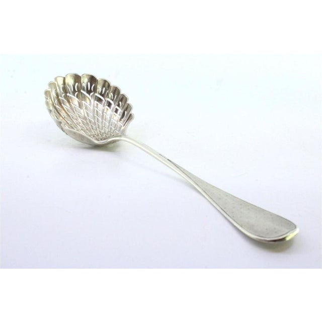 Shell-Shaped Silver Sprinkling Spoon with Guilloche Handle, in Very Good conditions. Designed before 1890 This piece has...