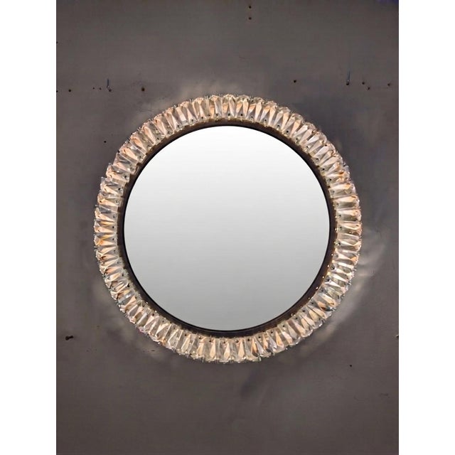 This circular wall mirror stands out for its opulent frame, composed of numerous faceted crystal prisms arranged in a...