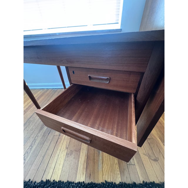 A beautifully constructed Danish modern teak executive desk featuring a drop leaf and a floating two-drawer cabinet....