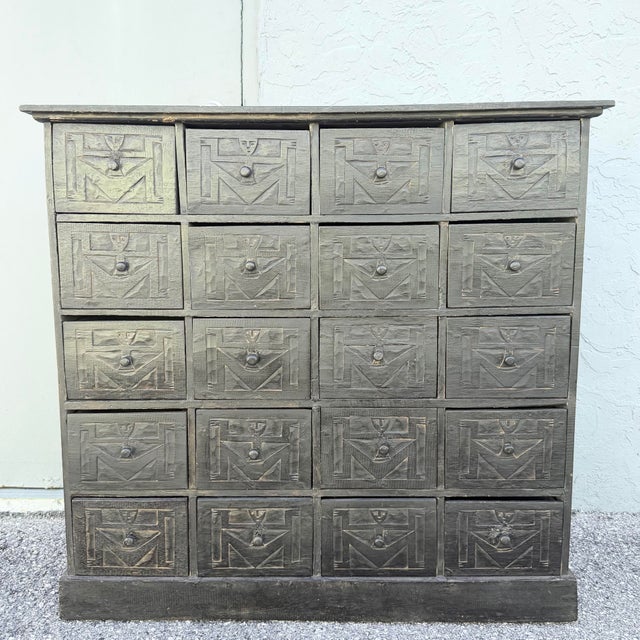 Unique vintage wooden apothecary chest featuring 20 individual drawers with hand-carved geometric and tribal-inspired...