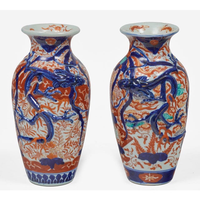 A small pair of Imari baluster shaped vases with flared necks decorated with boldly colored cobalt blue dragons, iron rust...