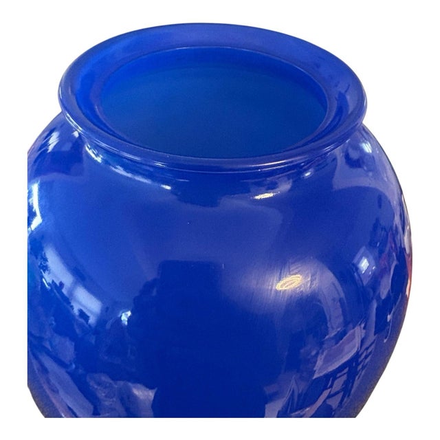 A striking cobalt blue glass vase with rounded shoulders, a gently tapered body, and a softly flared rim. Its vivid color...