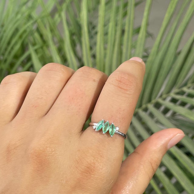 Handmade three-stone ring crafted in 925 sterling silver, featuring 0.89 carats of marquise-cut emeralds accented by 0.03...