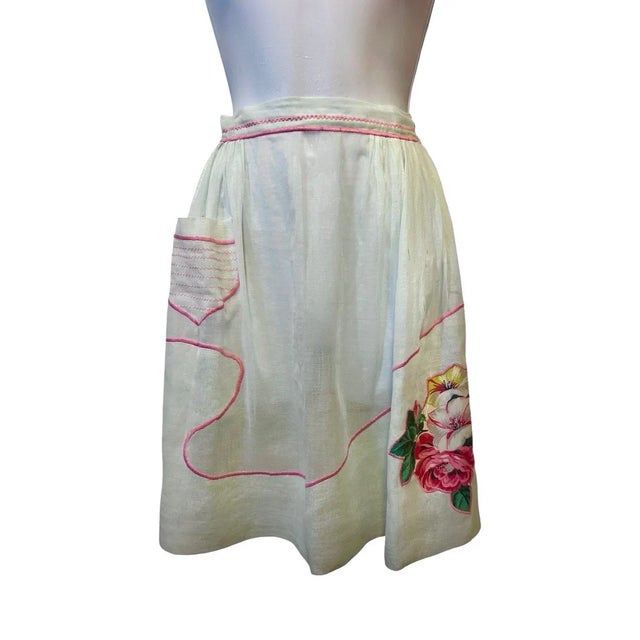 "A dreamy 1940s sheer hostess apron in the softest whisper-mint voile, finished with bubble-gum pink stitching and a hand-...