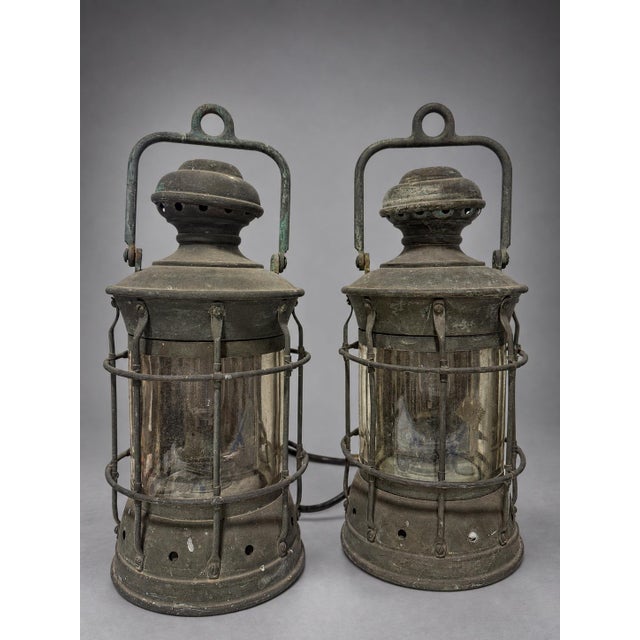 Set of four antique maritime lanterns, early 20th century. Each lantern is constructed with a cylindrical brass and copper...