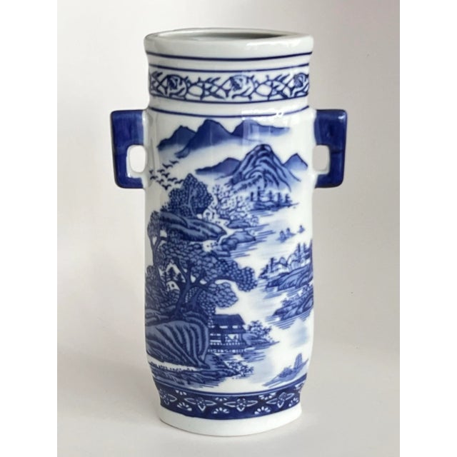 A graceful vintage Chinese blue and white porcelain vase featuring a serene hand-painted landscape scene in rich cobalt...