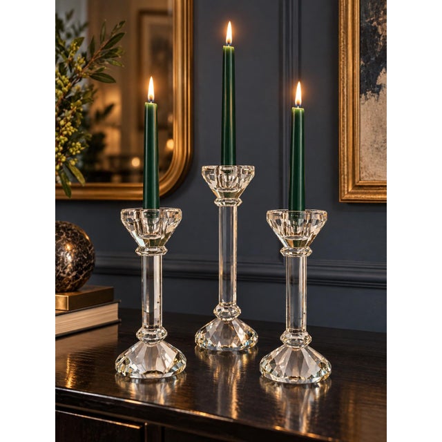 An elegant set of three clear crystal glass candlesticks featuring architectural stems, wide beveled candle cups, and...