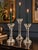 An elegant set of three clear crystal glass candlesticks featuring architectural stems, wide beveled candle cups, and...
