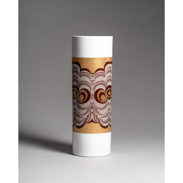 A tall porcelain floor vase with refined gold and grey Op Art decoration circling a glossy white cylindrical form. The...