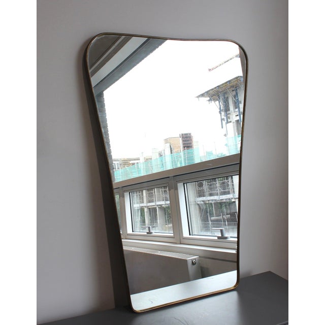 Mid-century italian wall mirror with brass frame (circa 1960s). The mirror is classically-shaped and certainly modern in...