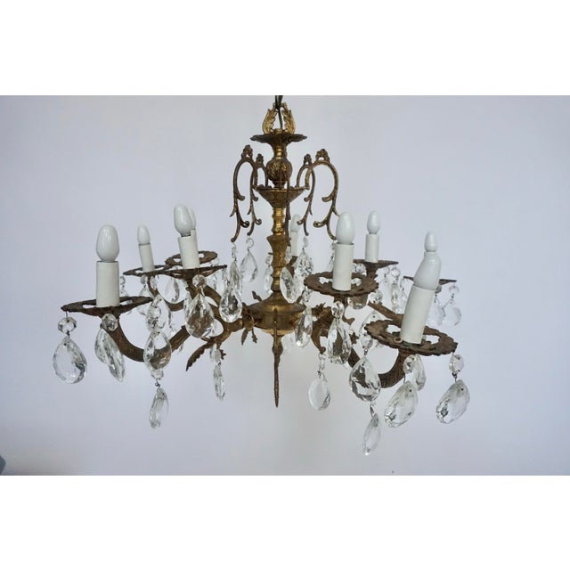 A beautifully substantial Spanish chandelier with a warm aged brass finish, sculptural cast detailing, and tiers of...