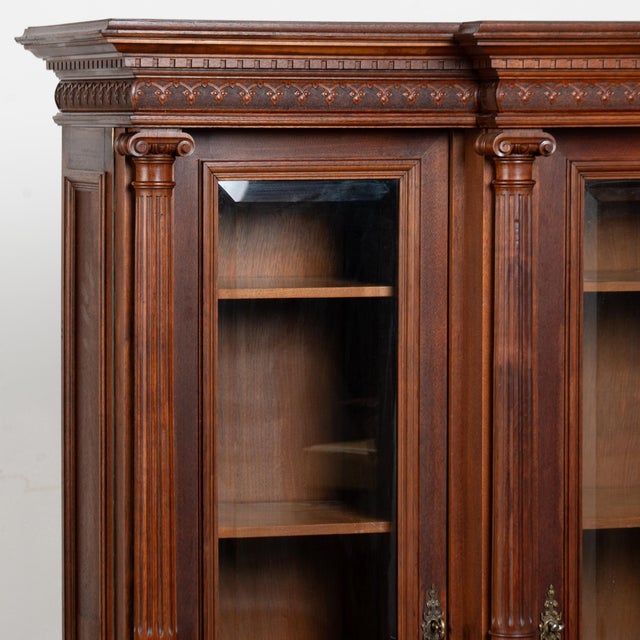 Small walnut display cabinet crafted in dark walnut. The bookcase features turned column details flanking three doors. The...