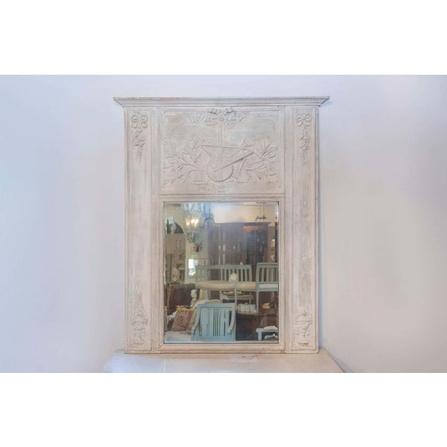 A French Louis XVI period trumeau mirror from circa 1790 with partial stripped finish and carved Liberal Arts allegory....
