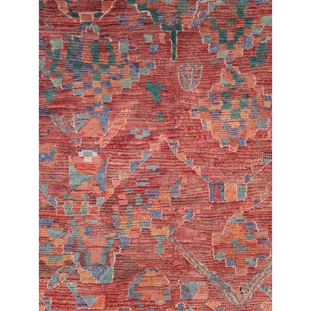 A vintage Moroccan rug in gallery format handmade during the late 20th century with tribal design elements over a deep red...