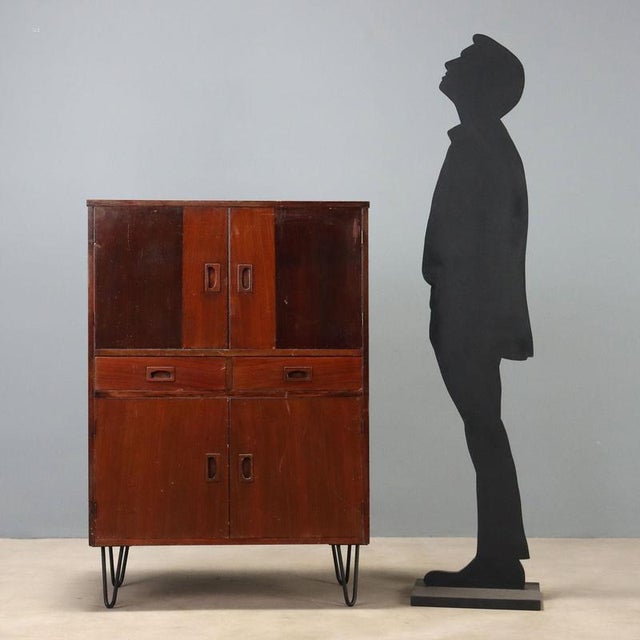 Vintage 1960s sideboard made of mahogany veneered wood, featuring hinged doors and central visible drawers. The structure...