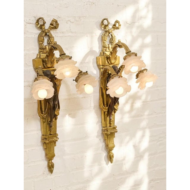 An extraordinary pair of vintage wall sconces with elaborate French neoclassical detailing and a wonderfully theatrical...