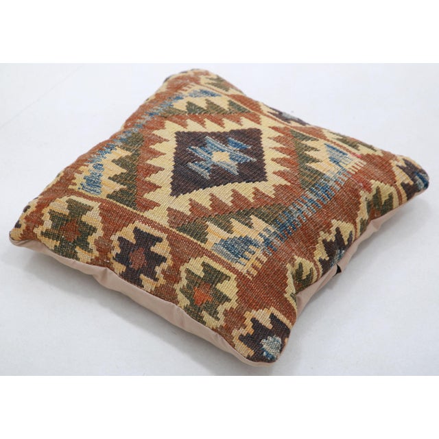 A one-of-a-kind handwoven Afghan wool kilim accent pillow featuring a concentric diamond medallion in rust, cream and...