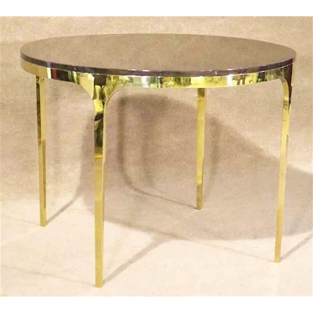Round dining table with polished brass base. Wood veneer top complimented by long slender brass legs.