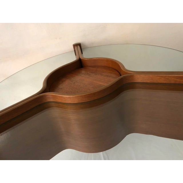 This coffee table features a central bar part adjustable in three positions. This piece is attributed to the mentioned...