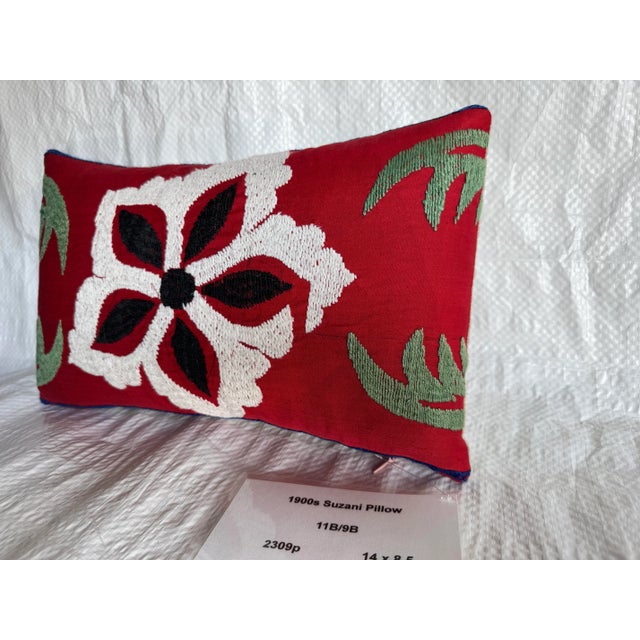 An exquisite early 1900s Suzani pillow featuring a striking red field with bold ivory and black floral embroidery accented...