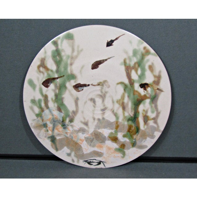 Large signed studio pottery decorative plate with an abstract aquatic composition of swimming fish, soft green plant...