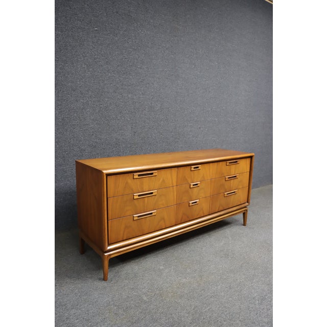 Mid-Century Modern walnut dresser attributed to United Furniture Co. Features nine drawers arranged in three columns, with...