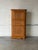 This corner storage cabinet features a triangular profile with three compartments. The facade is detailed with carved...