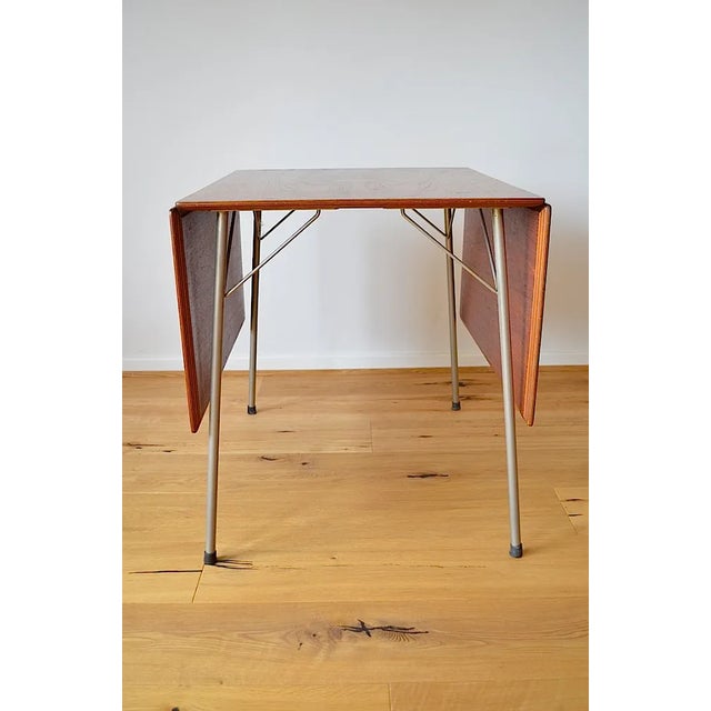 This foldable dining table, model 3601, is made of teak with a frame made of nickel -plated metal. - He was designed by...