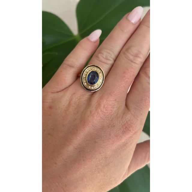 This stunning vintage ring from the 1960s features an 18-carat yellow gold band adorned with an oval Ceylon blue sapphire...