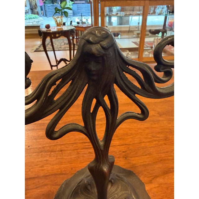 An early 20th-century Art Nouveau two-light candelabrum featuring sinuous whiplash curves, stylized floral decoration, and...