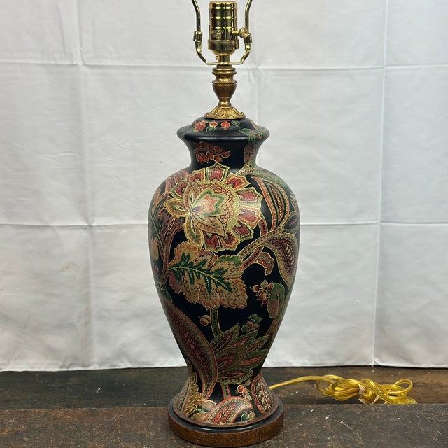 Signed Bradburn Gallery table lamp with brass finial and fittings. The base is hand painted in black, gold, green, and...