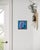 This artwork features a close-up depiction of an inflatable flamingo against a vibrant blue background, capturing the...