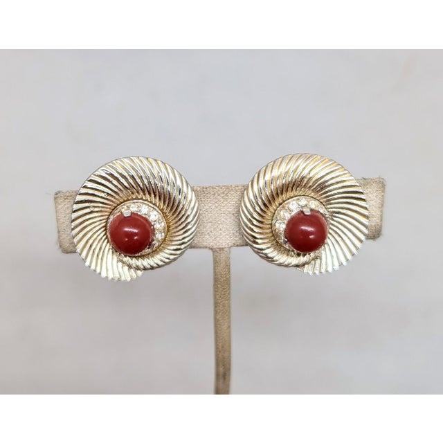Late 1950s ridged spiral with cabochon faux-carnelian center surrounded by small round clear rhinestones clip earrings....