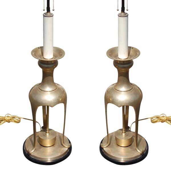 A pair of large brass table lamps in the manner of James Mont. Tripod form with round black bases.