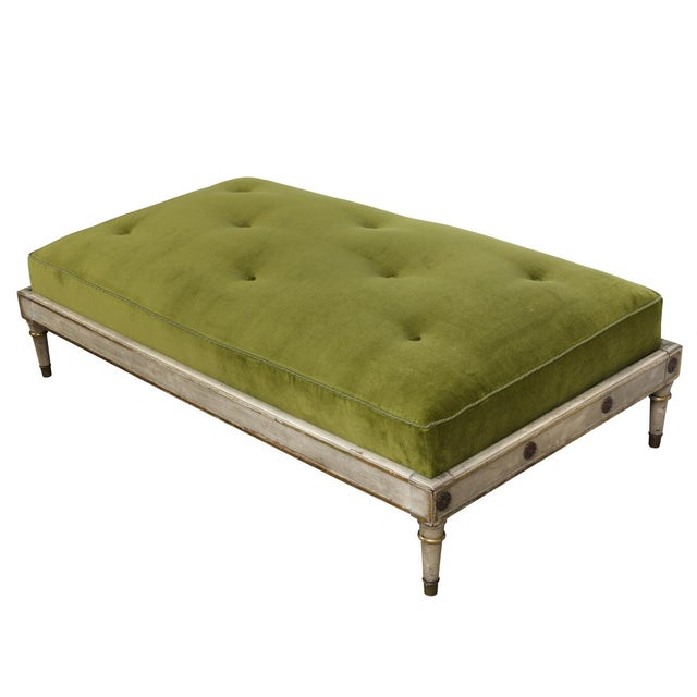 An oversized Italian ottoman featuring a beautifully hand painted and gilt decorated carved wood frame with a green velvet...